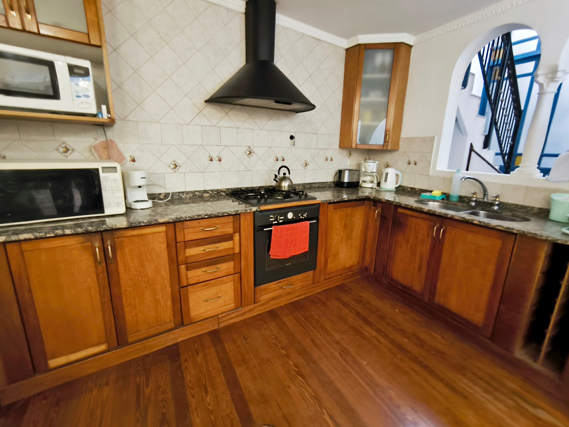 Large kitchen of Casa Jacarandá with wooden cabinets, granite counter and gas stove