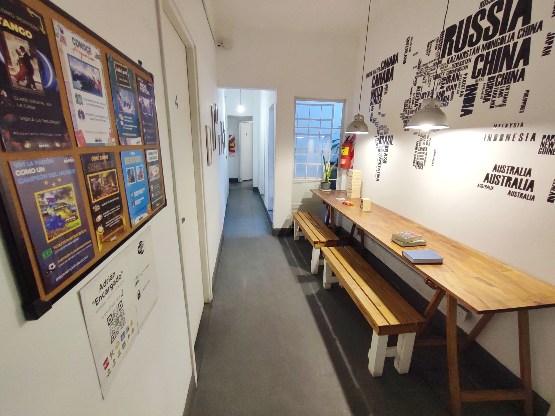 Study space of Casa Tango with a long wooden table, benches and a world-map wall